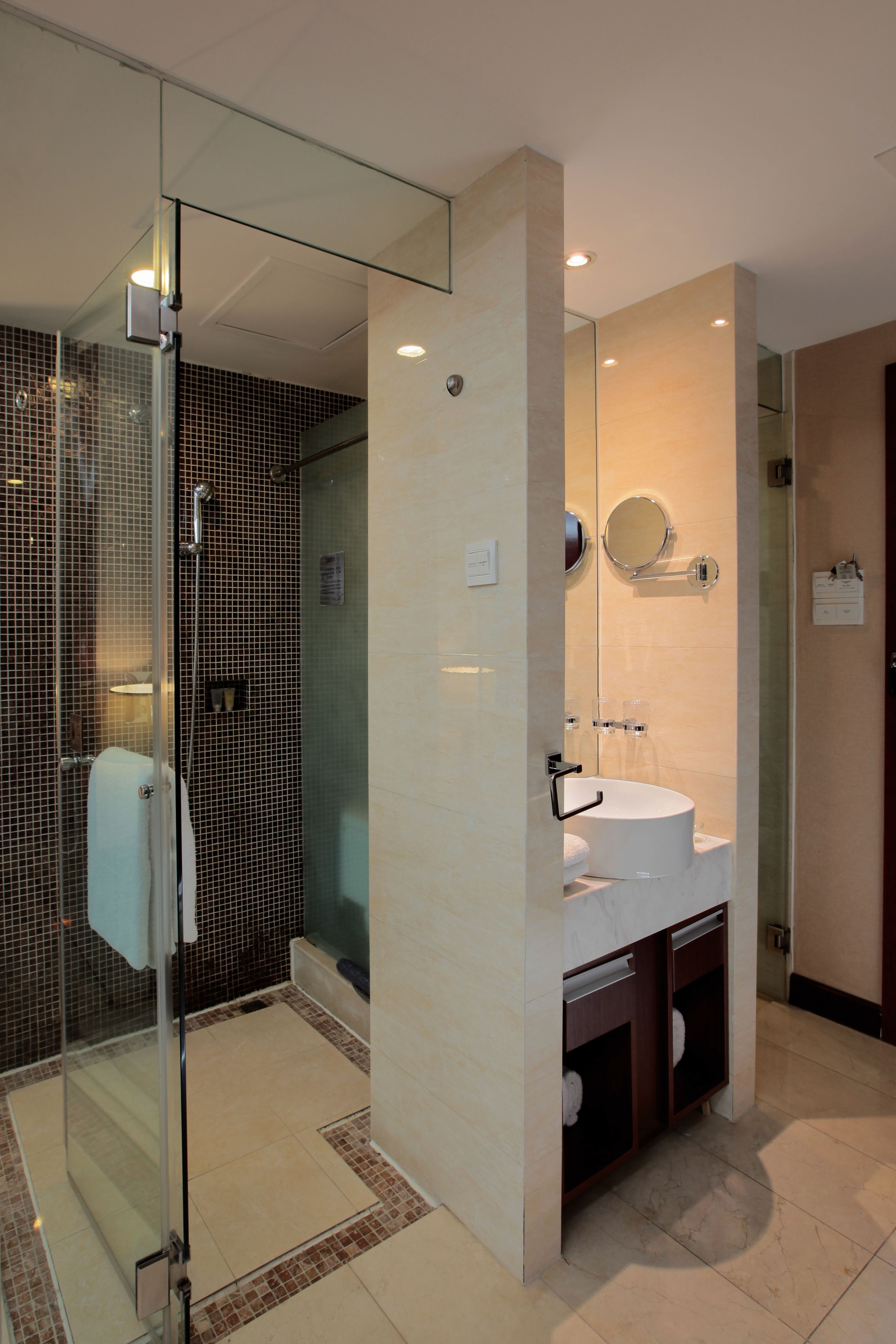 A modern bathroom with a glass shower enclosure, a white sink, and a mirror above it.