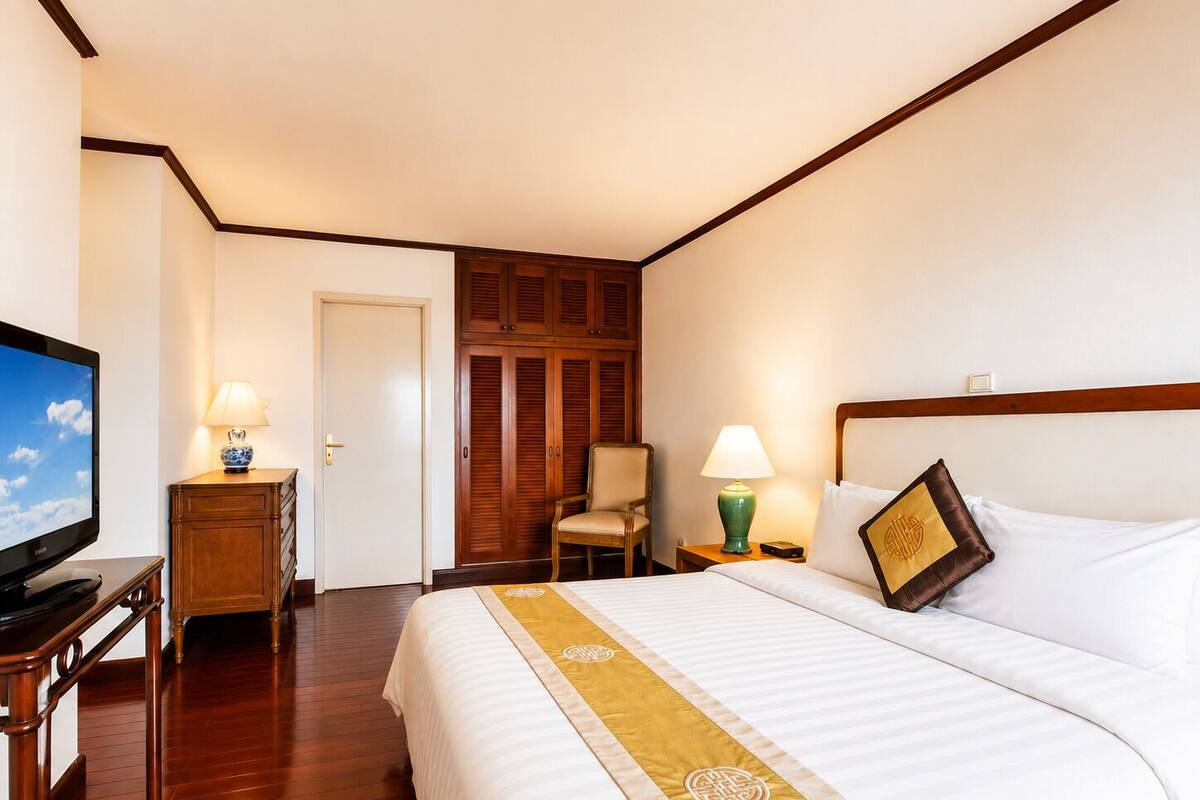 Una habitación de hotel con cama, televisor, escritorio, silla y armario.