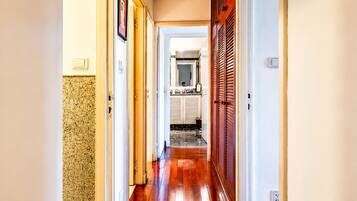 A hallway with wooden flooring, white walls, and a ceiling light.