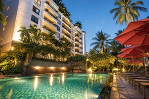 A hotel with a swimming pool, palm trees, and red umbrellas. - Saigon Domaine Luxury Residences (Ho Chi Minh City)