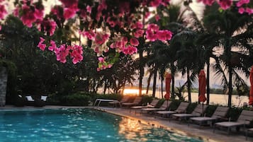 Una piscina al aire libre, sombrillas, sillones reclinables de piscina