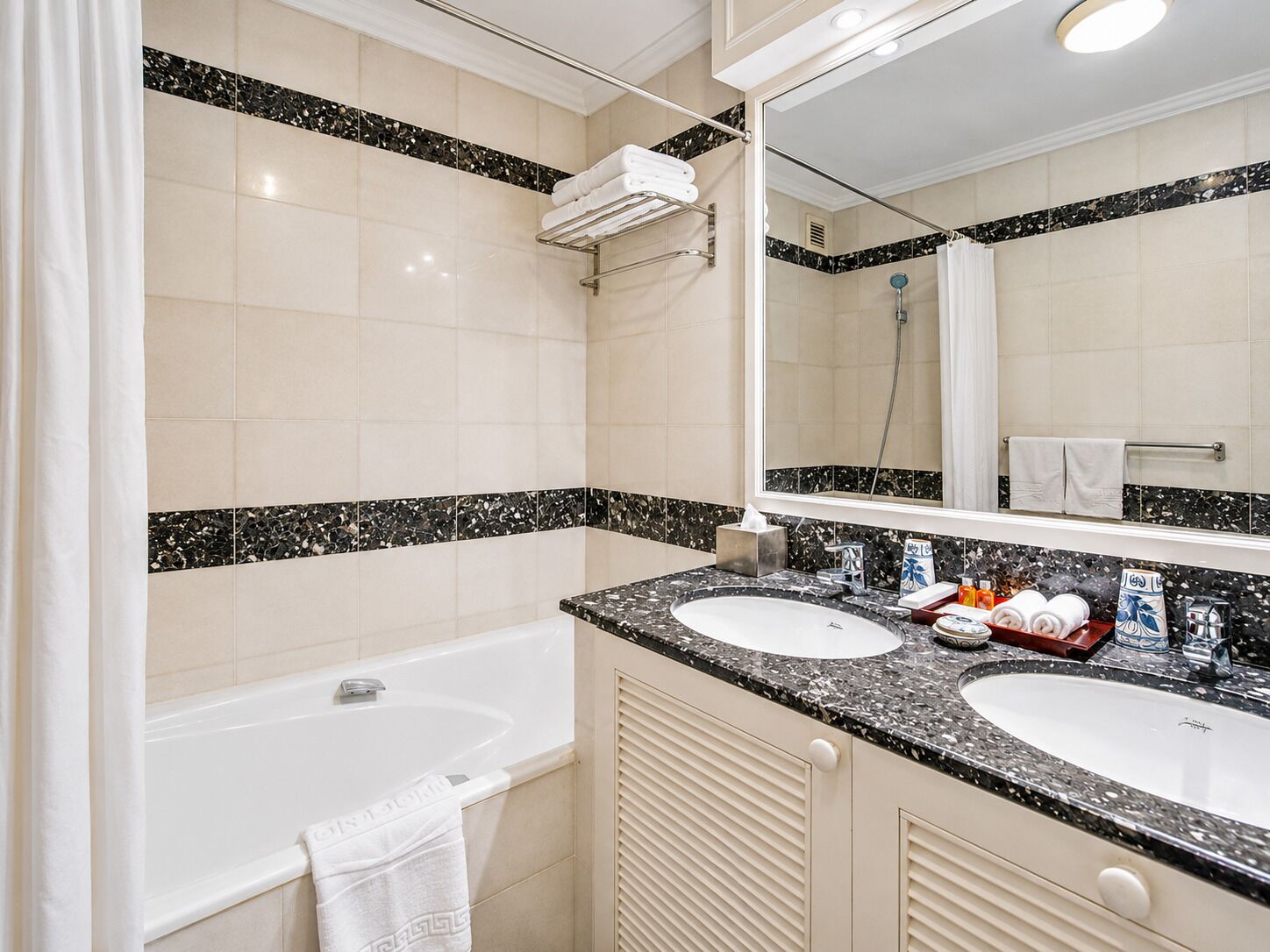 A bathroom with two sinks, a bathtub, a shower, and a large mirror.