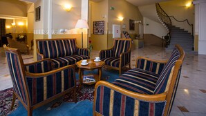 A lobby with striped armchairs, a coffee table, and a staircase. - Hotel Tyl (Prague)