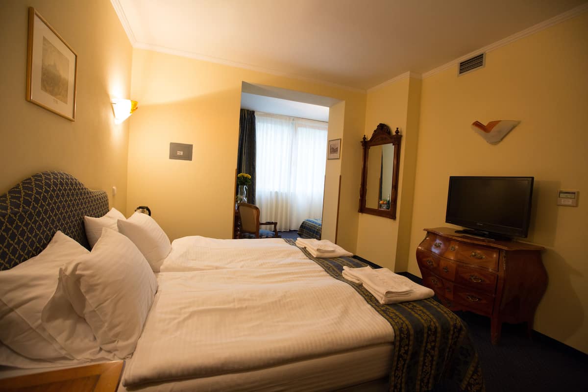 A hotel room with a large bed, a television, a dresser, and a mirror.