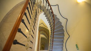 A spiral staircase with ornate balusters and a wooden handrail. - Hotel Tyl (Prague)