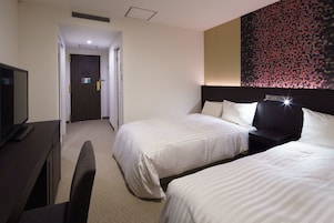 Habitación de hotel con dos camas, un escritorio con televisor y una obra de arte abstracta de gran tamaño en la pared.