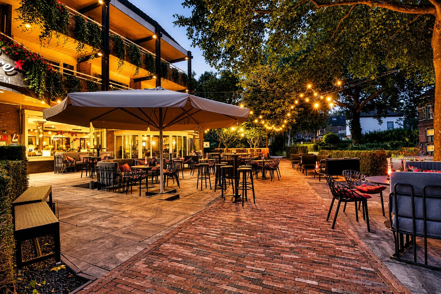 An outdoor patio area with tables and chairs, a covered seating area, and string lights.