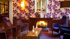 A lobby with purple floral wallpaper, a fireplace, and seating arrangements. - Hotel Hof Van Gelre by Flow (Lochem)