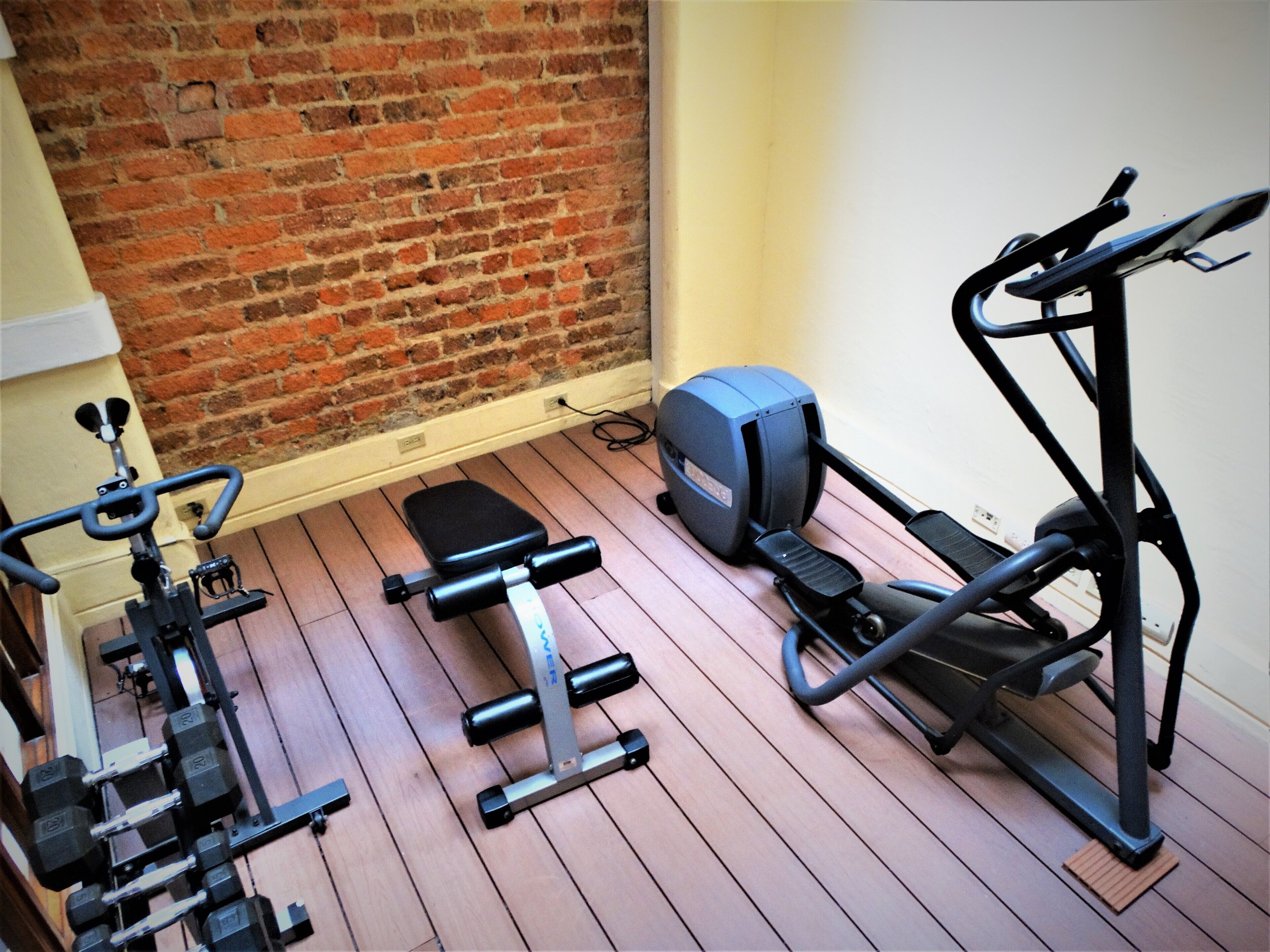 Une salle de sport à domicile équipée d’un tapis de course, d’un vélo d’appartement et d’un banc de musculation.