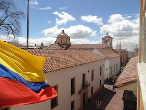 A street view with buildings featuring terracotta roofs and a prominent flag. - Hotel de la Opera (Bogotá)