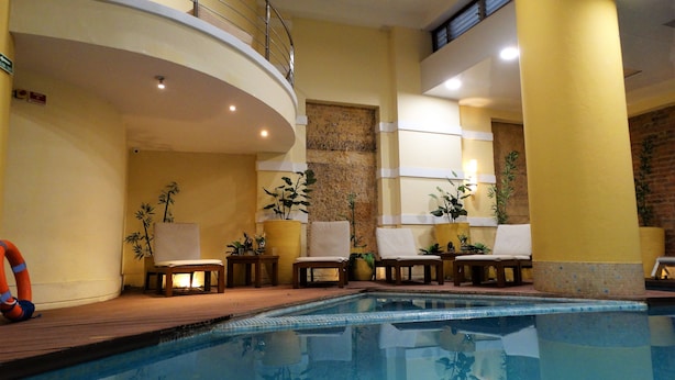 A pool area with a curved balcony, lounge chairs, and potted plants. - Hotel de la Opera (Bogotá)