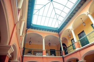 Un atrio de varios niveles con techo de cristal, columnas blancas y balcones con barandillas.