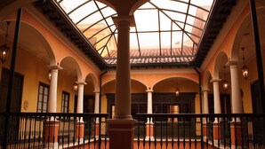 A spacious atrium with a high ceiling and a glass dome, featuring columns and a railing. - Hotel de la Opera (Bogotá)