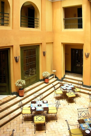 A courtyard with outdoor seating, a staircase, and a building facade with balconies and doors.