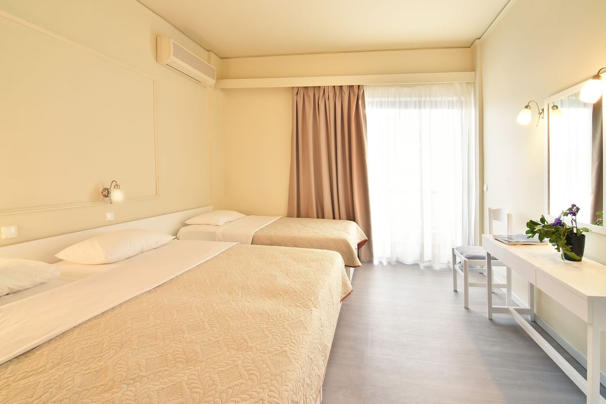 A hotel room with two beds, a desk, a chair, and a large mirror.