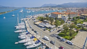 Un puerto deportivo con numerosas embarcaciones amarradas a lo largo de la costa, conectado por una carretera con edificios y vegetación cerca.