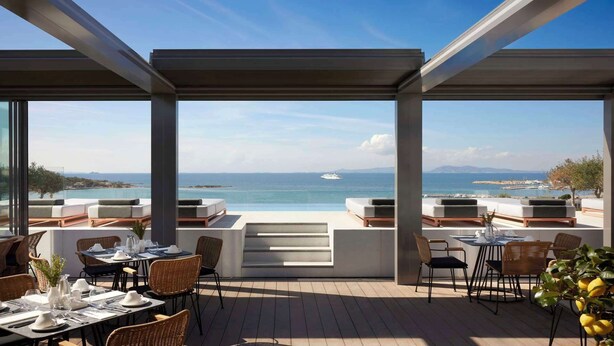 An outdoor dining area with a view of the sea and a yacht in the distance. - Dusit Suites Athens (Glyfada)