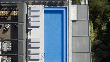 Piscina no terraço com interior azul, rodeada por espreguiçadeiras e mesas.