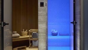 A modern hotel corridor with a wooden floor, a blue-lit room, and a wooden bench. - Dusit Suites Athens (Glyfada)