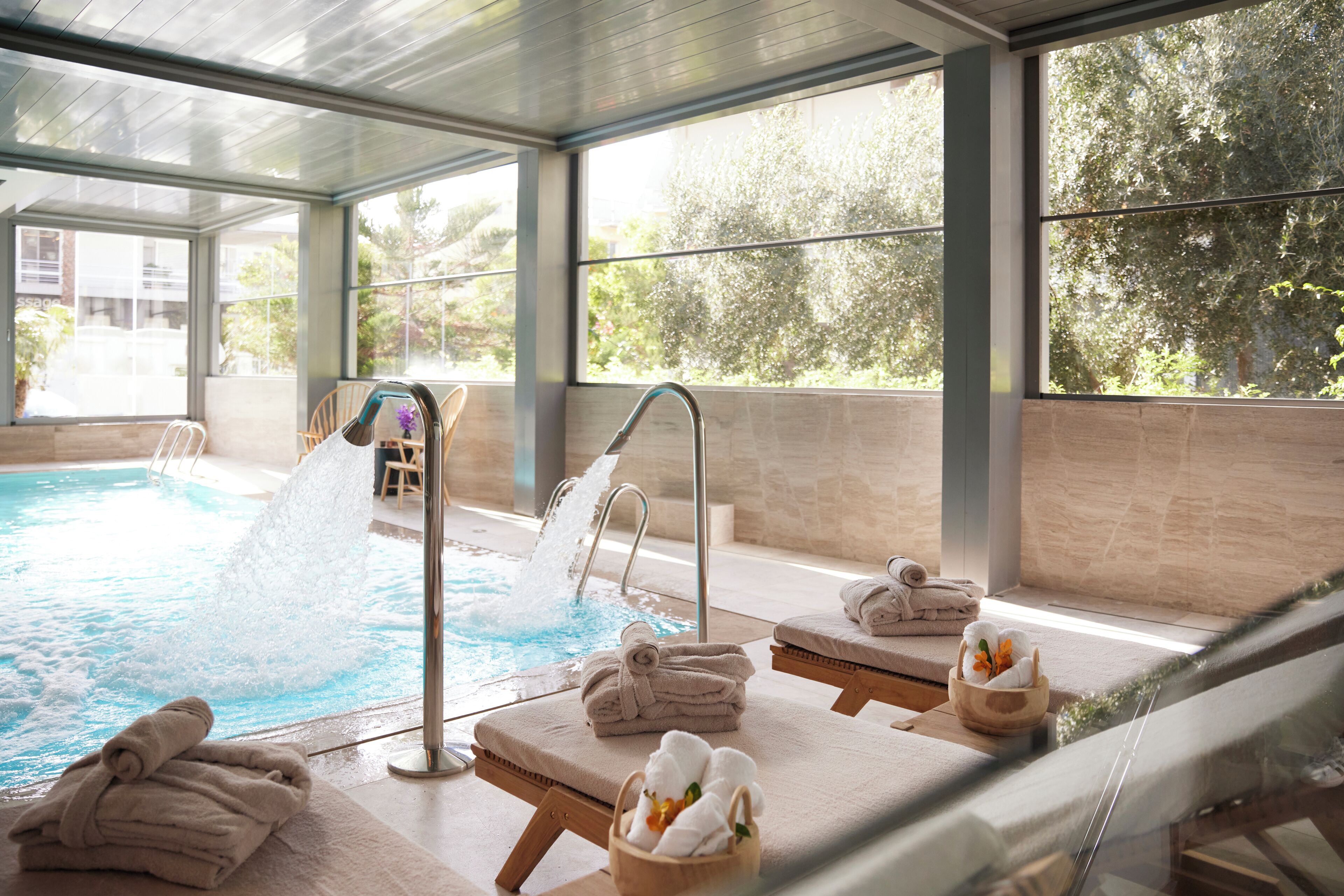 A modern indoor pool area with a water slide, lounge chairs, and towels.