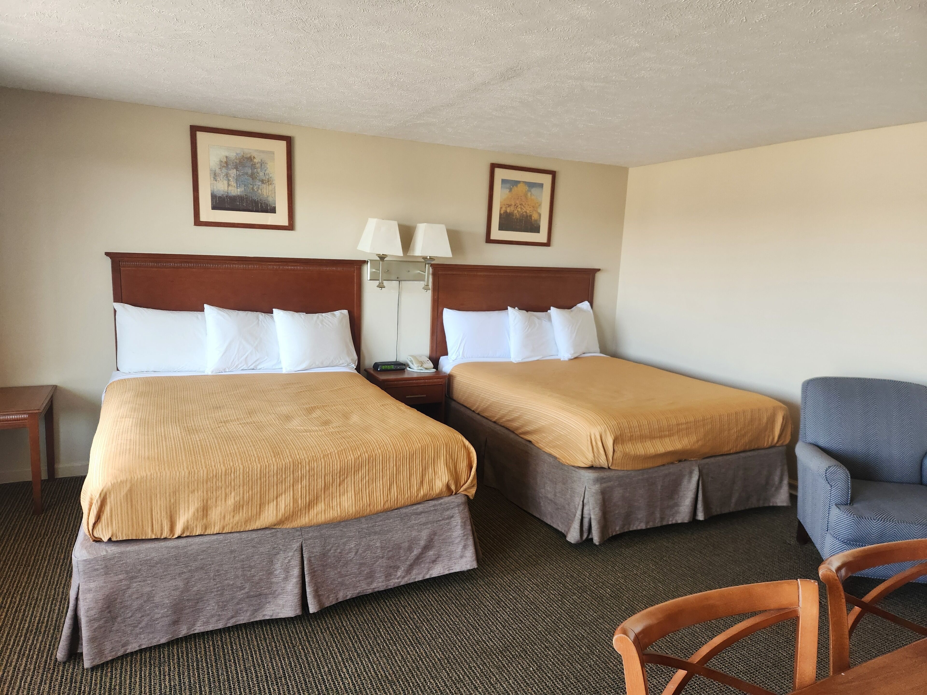 Habitación de hotel con dos camas, un escritorio, una silla y dos lámparas fijadas a la pared.