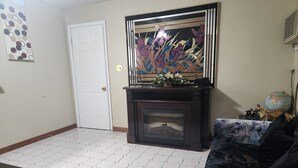 A living room with a fireplace, a door, a globe, and a patterned rug. - Royal Motel (Hermitage)