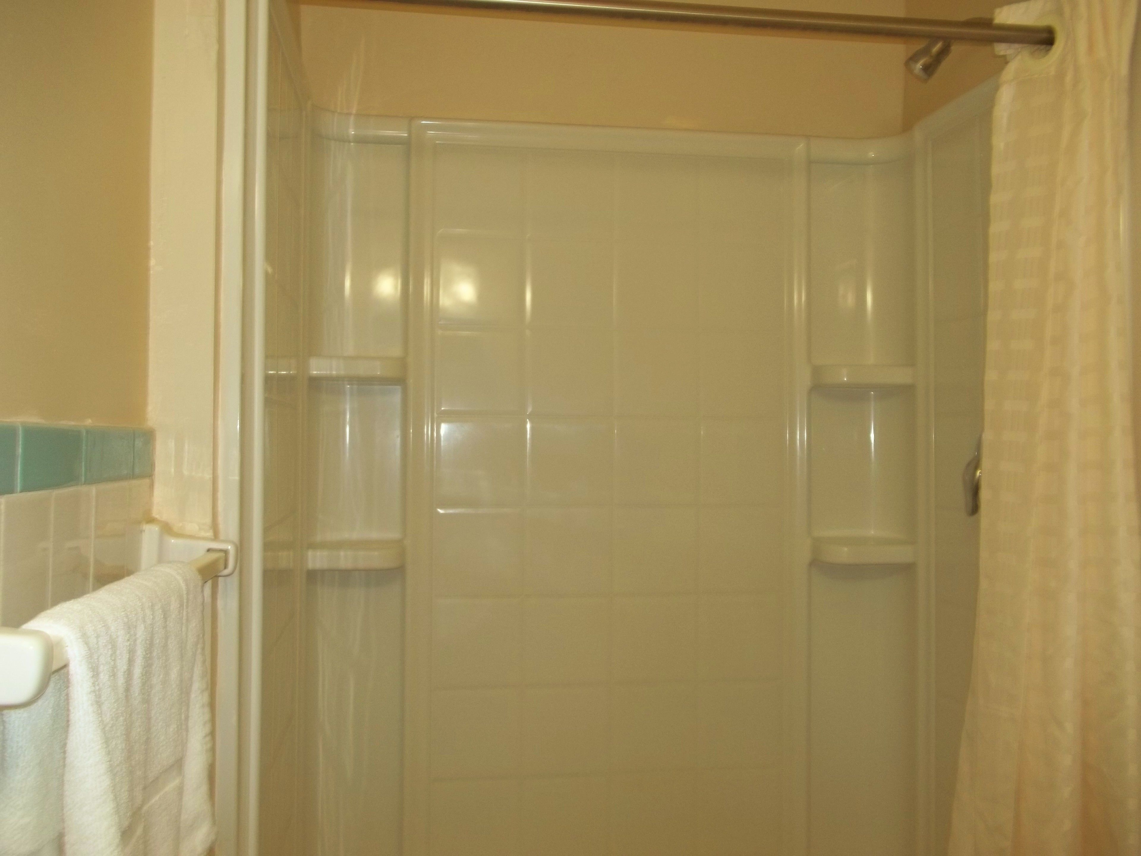 Casa de banho com cabine de duche, porta-toalhas e parede revestida a mosaicos.