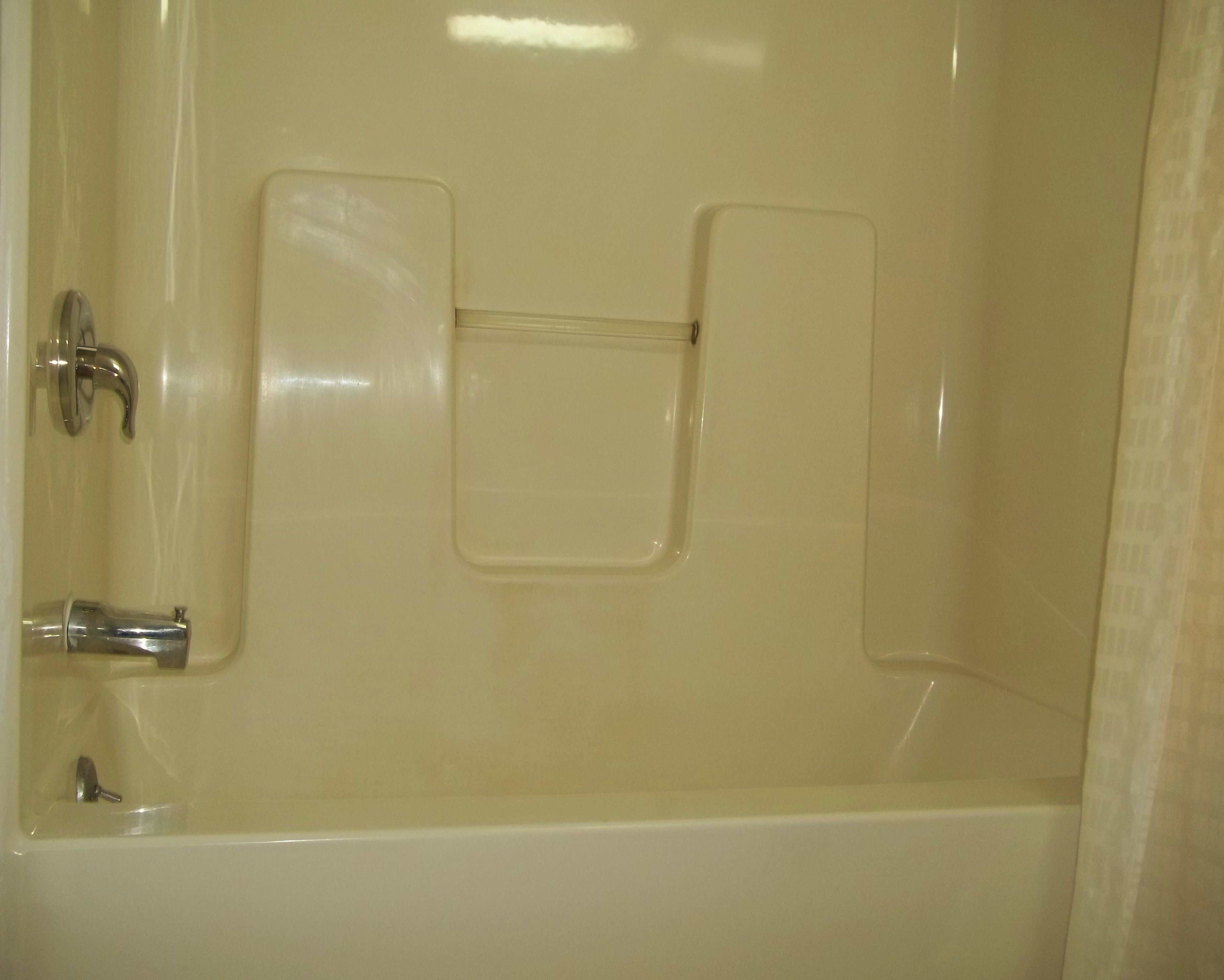 Een bad met een kraan en bedieningspaneel voor de douche.