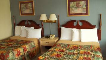 A hotel room with two beds, each with floral bedspreads, a nightstand with lamps, and framed artwork on the walls.