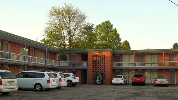 A multi-story motel with a parking lot. - Royal Motel (Hermitage)