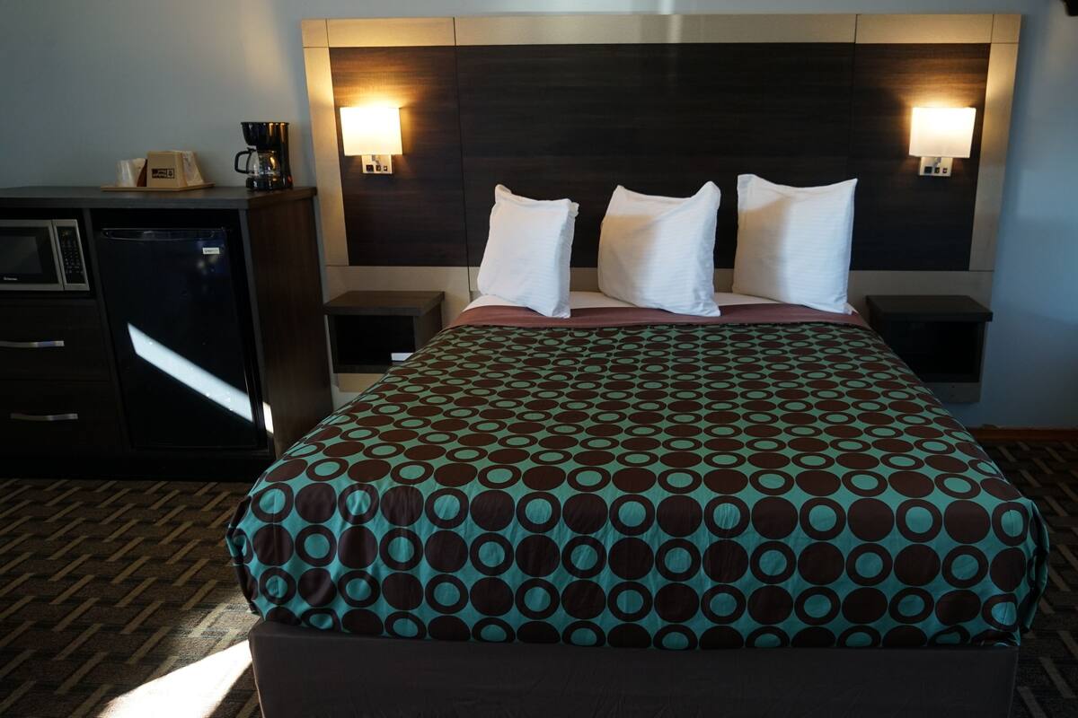 A hotel room with a bed, two bedside tables, a coffee maker, and a microwave.