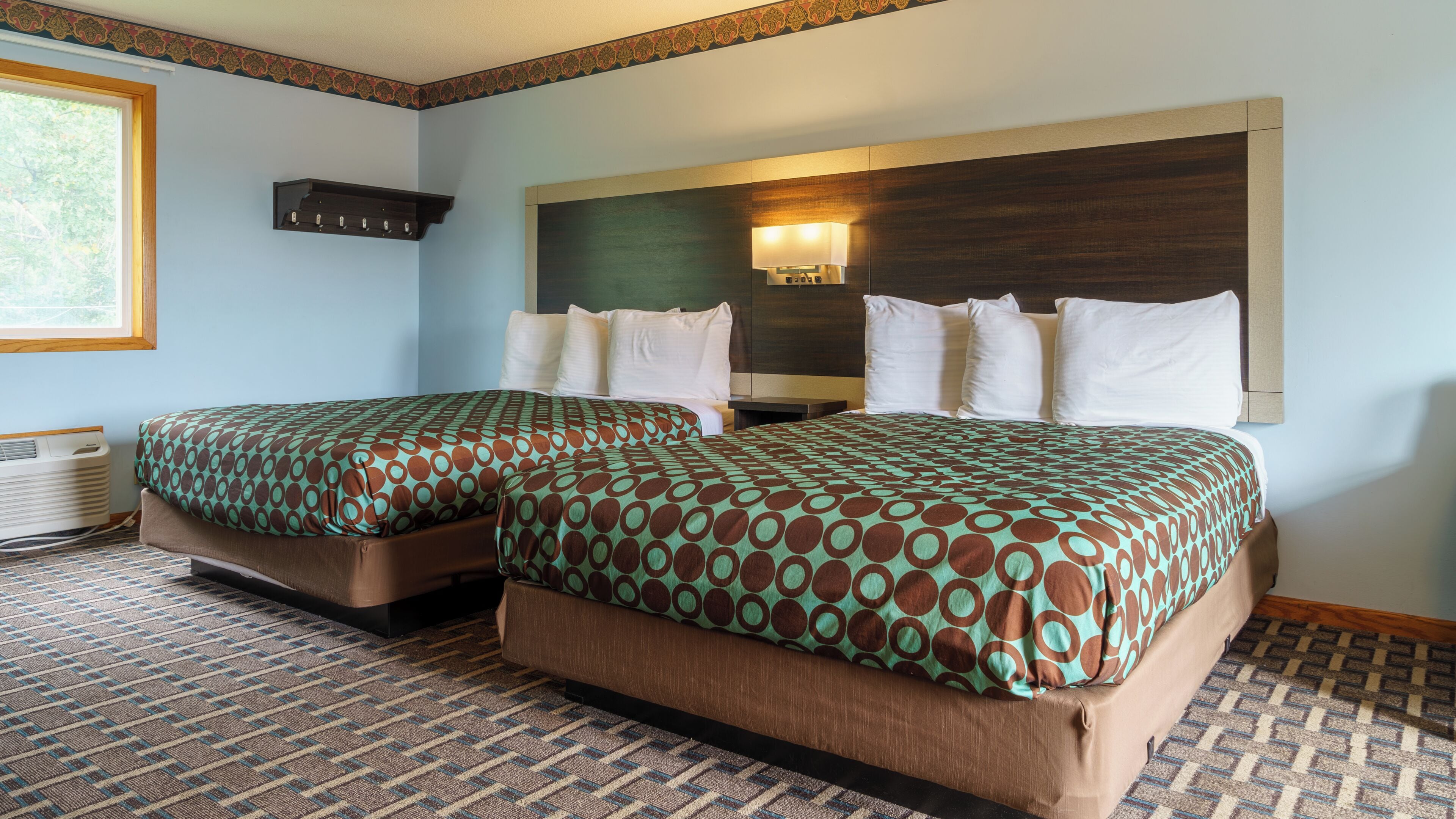 Habitación de hotel con dos camas, un espejo grande y una ventana.