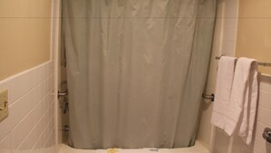 A bathroom with a shower curtain, a bathtub, and a towel rack with towels.