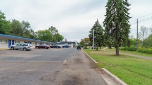 A motel with a parking lot, a grassy area, and trees. - Budget Host Inn Fridley (Fridley)