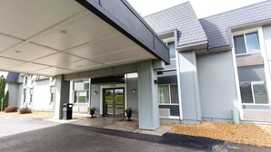 A modern building with a covered entrance, a number 1255 sign, and a trash bin.