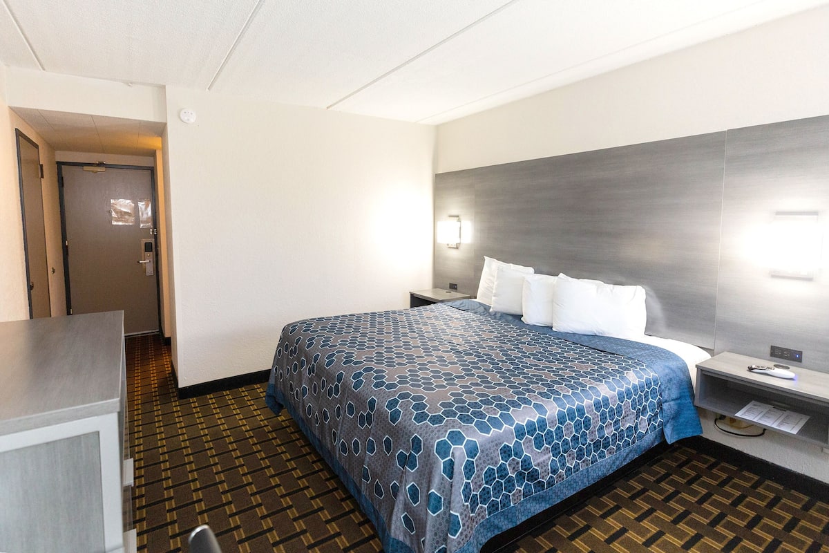 Ein Hotelzimmer mit einem großen Bett, einem Schreibtisch und einem Nachttisch.