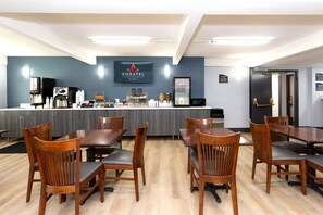 A restaurant with wooden tables and chairs, a counter with a coffee machine, and a sign reading "CORATEL". - Coratel Inn & Suites by Jasper Mankato (Mankato)