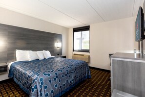 A hotel room with a bed, a nightstand, a TV, and a window. - Coratel Inn & Suites by Jasper Mankato (Mankato)