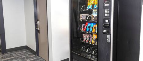 A vending machine with snacks and drinks in a hallway.