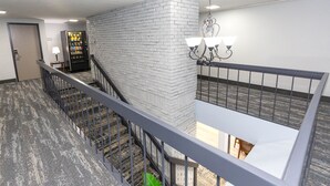 A hotel lobby with a staircase, a vending machine, and a chandelier. - Coratel Inn & Suites by Jasper Mankato (Mankato)