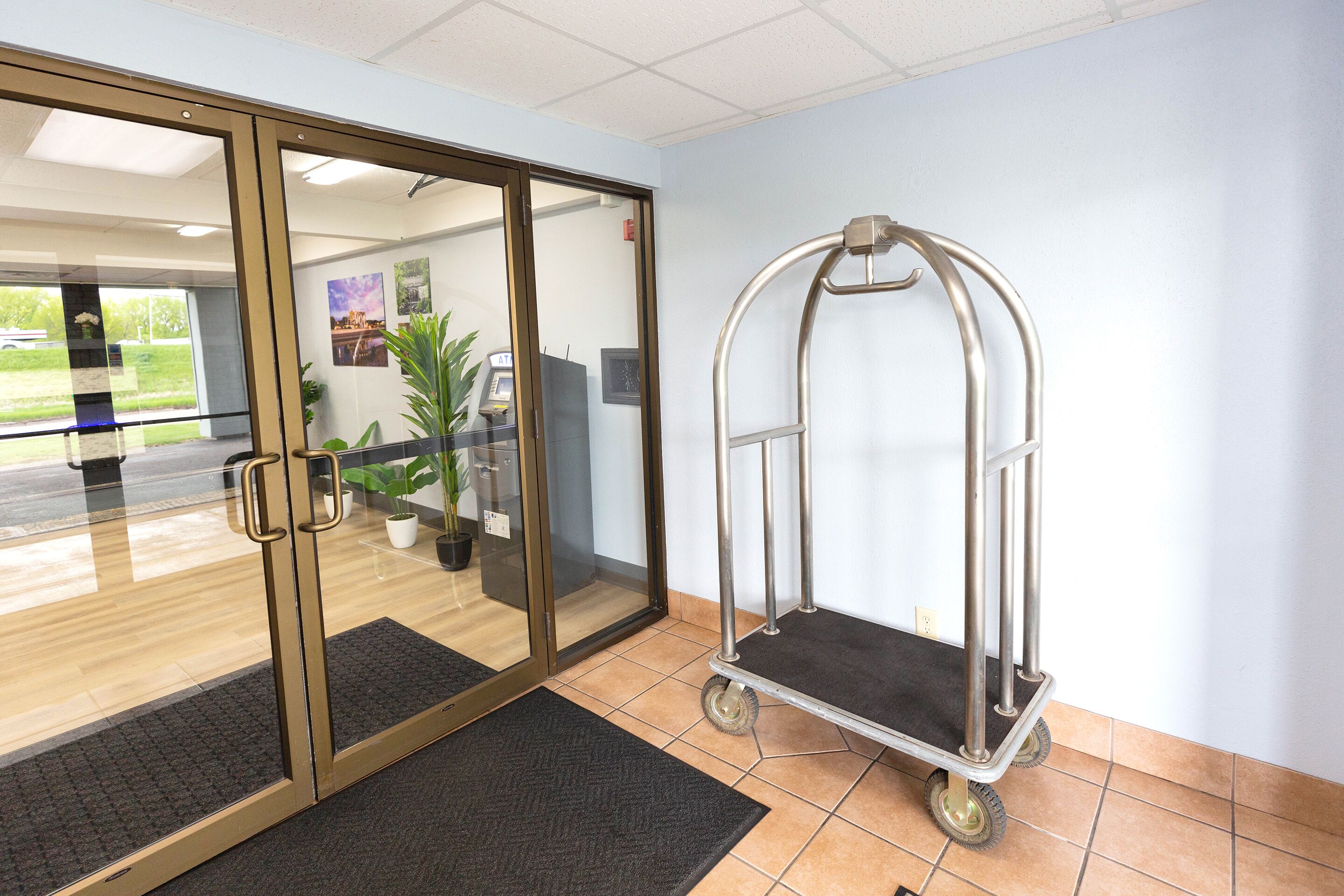 A reception area with a glass door, a cart, and a tiled floor.