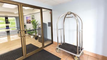 A reception area with a glass door, a cart, and a tiled floor.