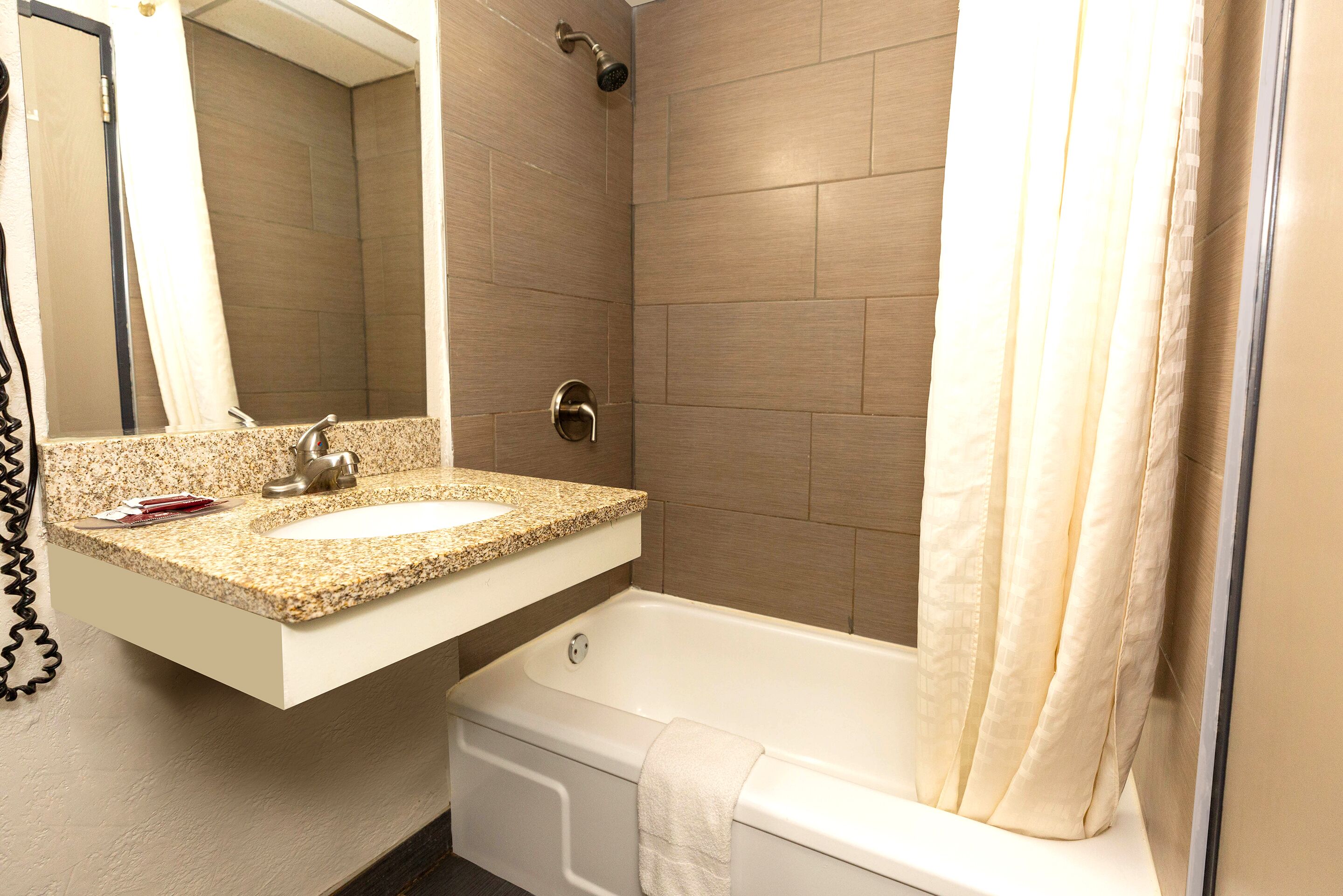 Un baño con lavamanos, espejo, ducha y bañera.