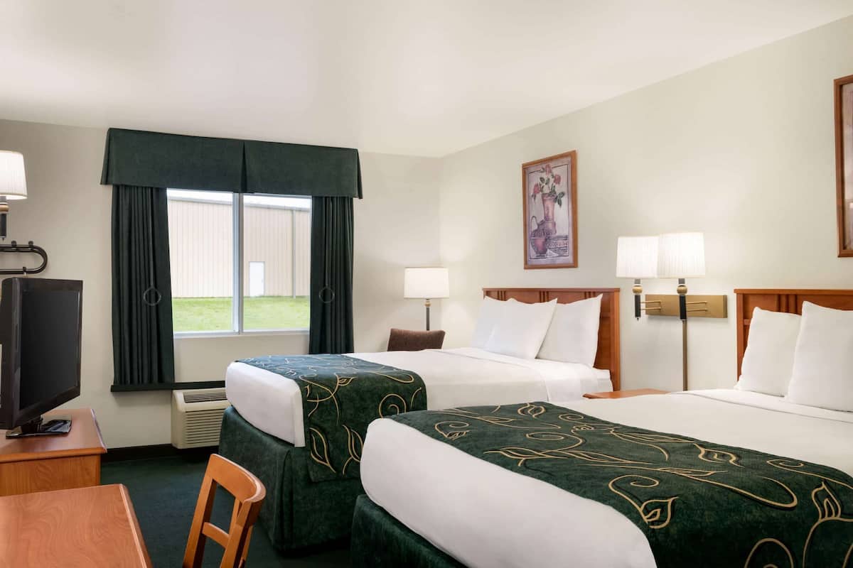Een hotelkamer met twee bedden, een televisie, een bureau en een raam met gordijnen.