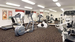 Un gimnasio con cintas de correr, elípticas y equipo de pesas.