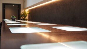 A long reception desk with a wooden finish and a modern light fixture above it.