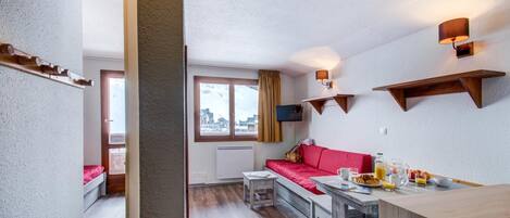 Un espacio habitable compacto con kitchenette, zona de comedor y sofá.