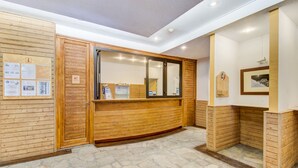 A reception area with wooden paneling, a reception desk, and a stone-tiled floor. - Vacancéole - Le Borsat IV (Tignes)