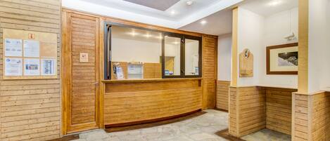 A reception area with wooden paneling, a reception desk, and a stone-tiled floor.
