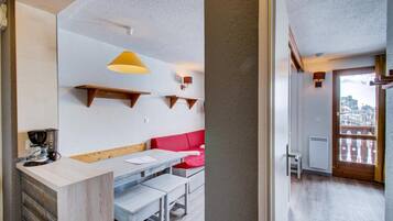A modern kitchen with a wooden counter, a red sofa, and a hanging light fixture.